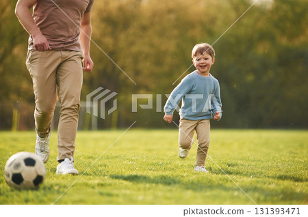 Teaching how to play a soccer. Happy father with son are having fun on the field at summertime Teaching how to play a soccer. Happy father with son are having fun on the field at summertime 131393471