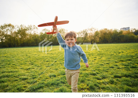 Running with toy plane. Cute happy little boy is on the field outdoors Running with toy plane. Cute happy little boy is on the field outdoors 131393516
