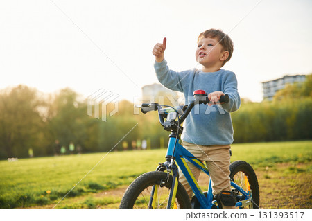 On the bicycle. Cute happy little boy is on the field outdoors On the bicycle. Cute happy little boy is on the field outdoors 131393517