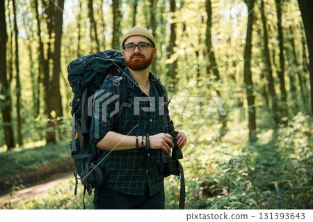 Tourist with binoculars. Bearded man is in the forest at daytime 131393643