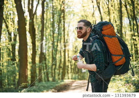 In glasses and with backpack. Bearded man is in the forest at daytime In glasses and with backpack. Bearded man is in the forest at daytime 131393679