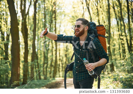 In glasses and with backpack. Bearded man is in the forest at daytime In glasses and with backpack. Bearded man is in the forest at daytime 131393680