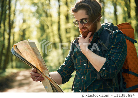 Old fashioned paper map in hands. Bearded man is in the forest at daytime Old fashioned paper map in hands. Bearded man is in the forest at daytime 131393684