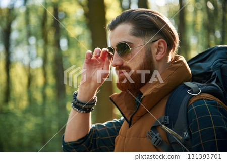In cool sunglasses. Bearded man is in the forest at daytime In cool sunglasses. Bearded man is in the forest at daytime 131393701