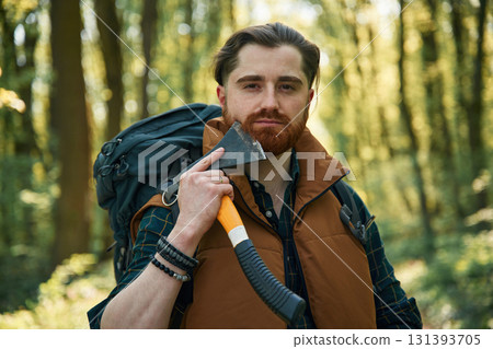 Shaving by using an axe. Bearded man is in the forest at daytime 131393705