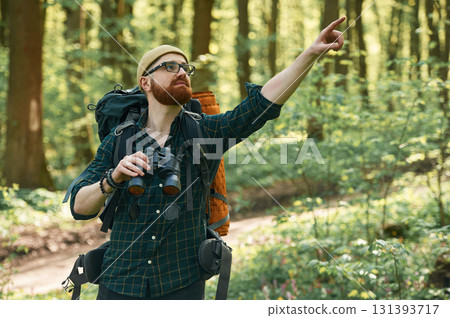 Discovering new place with binoculars. Bearded man is in the forest at daytime 131393717