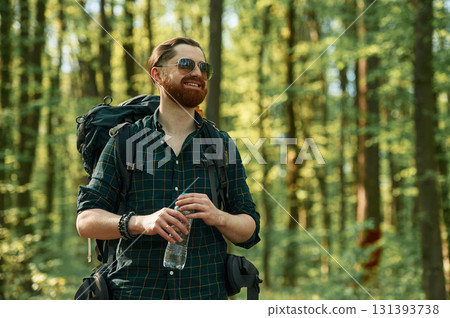 In cool sunglasses. Bearded man is in the forest at daytime 131393738