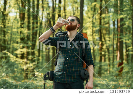 In cool sunglasses. Bearded man is in the forest at daytime 131393739