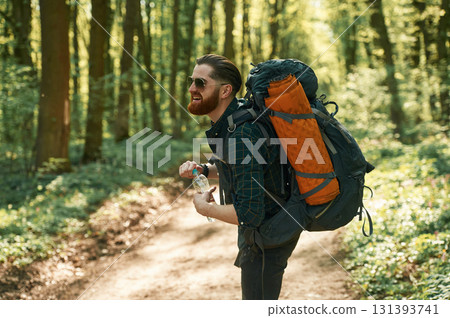 Bottle of water, holding. Bearded man is in the forest at daytime Bottle of water, holding. Bearded man is in the forest at daytime 131393741