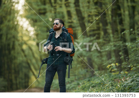 On the pathway with binoculars. Bearded man is in the forest at daytime On the pathway with binoculars. Bearded man is in the forest at daytime 131393753