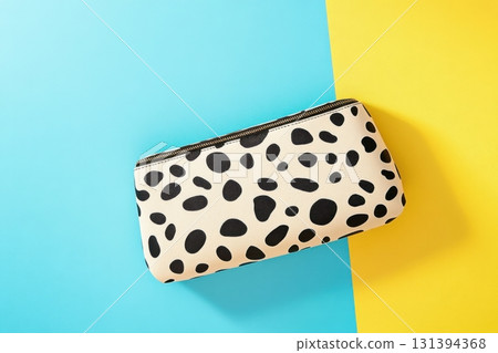 Leopard-print clutch bag with sleek black leather details on textured surface illuminated by bold studio lighting 131394368