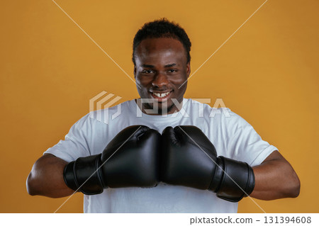 Professional boxer in gloves. Black guy is against yellow background Professional boxer in gloves. Black guy is against yellow background 131394608