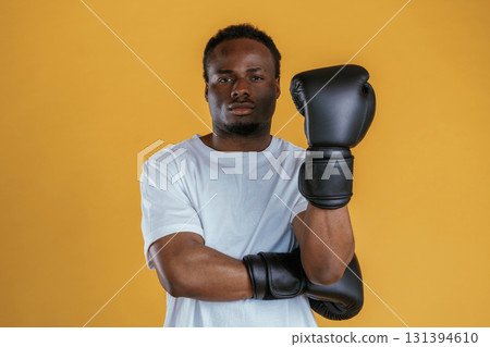 Professional boxer in gloves. Black guy is against yellow background Professional boxer in gloves. Black guy is against yellow background 131394610