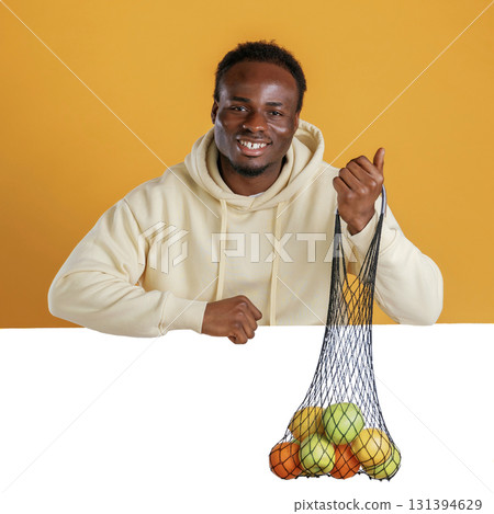 Smiling, holding bunch of fruits against white copy space. Black guy is on yellow background 131394629