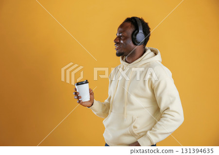 Coffee and headphones. Black guy is against yellow background 131394635