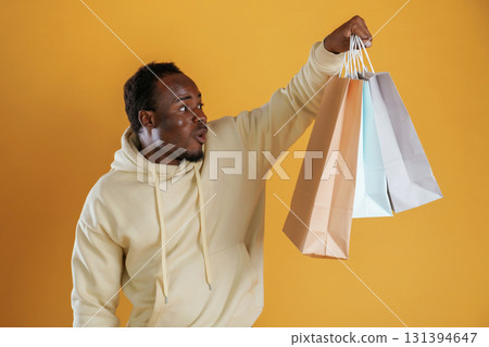 Crazy sales, with shopping bags. Black guy is against yellow background Crazy sales, with shopping bags. Black guy is against yellow background 131394647