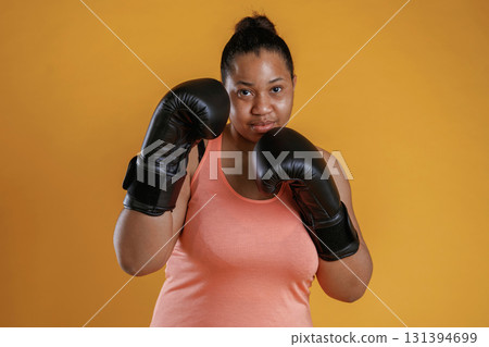 Boxer is ready to fight. African American woman is in the studio against yellow background Boxer is ready to fight. African American woman is in the studio against yellow background 131394699