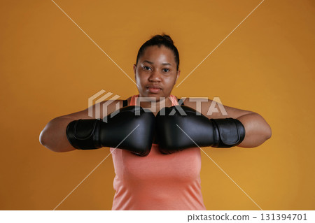 Boxer is ready to fight. African American woman is in the studio against yellow background 131394701