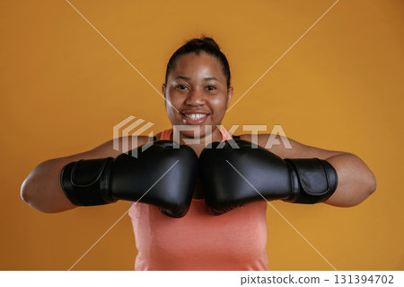 Boxer is ready to fight. African American woman is in the studio against yellow background 131394702