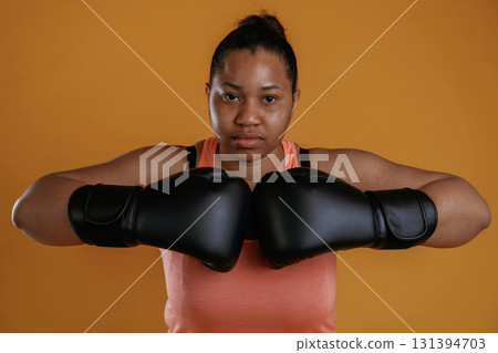 Boxer is ready to fight. African American woman is in the studio against yellow background 131394703
