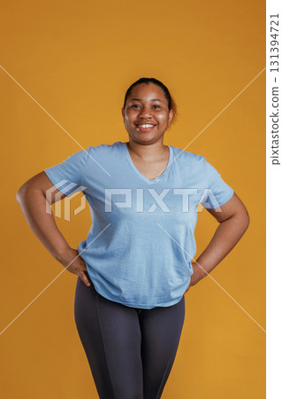 Standing and posing. African American woman is in the studio against yellow background 131394721