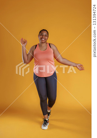 In fitness sportive clothes. African American woman is in the studio against yellow background In fitness sportive clothes. African American woman is in the studio against yellow background 131394724