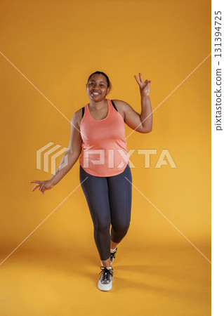 In fitness sportive clothes. African American woman is in the studio against yellow background In fitness sportive clothes. African American woman is in the studio against yellow background 131394725