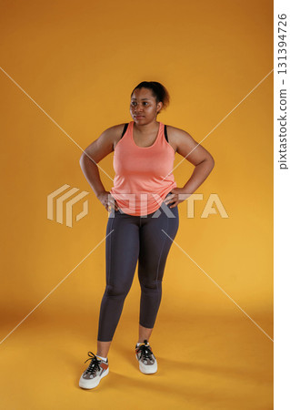 In fitness sportive clothes. African American woman is in the studio against yellow background In fitness sportive clothes. African American woman is in the studio against yellow background 131394726