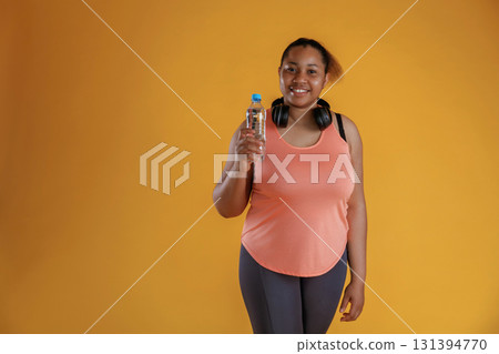 Bottle of water, break, standing with headphones on the neck. African American woman is in the studio 131394770
