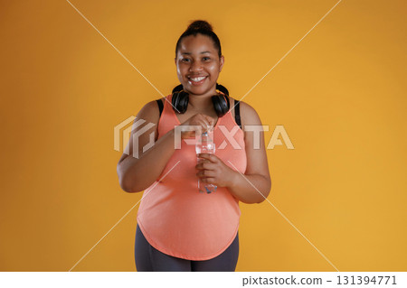 Bottle of water, break, standing with headphones on the neck. African American woman is in the studio 131394771