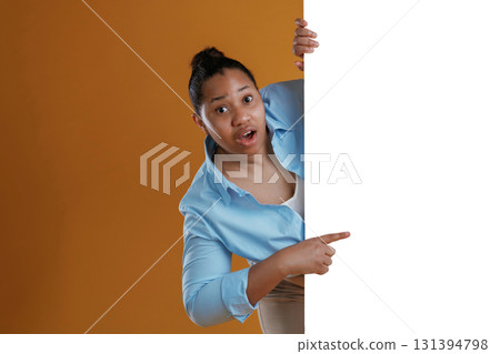 White copy space wall, hiding behind it. African American woman is in the studio against yellow background 131394798