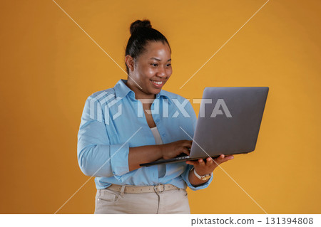 Manager with laptop. African American woman is in the studio against yellow background Manager with laptop. African American woman is in the studio against yellow background 131394808