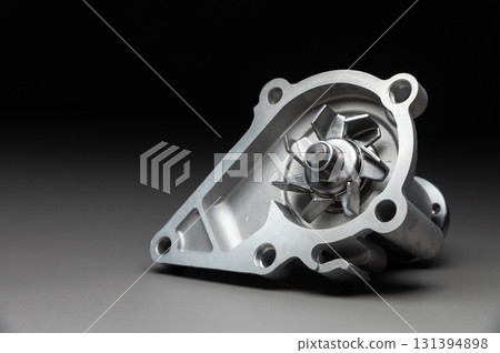 A new, shiny aluminum engine coolant pump on a gray gradient background. Contrast backlighting. 131394898