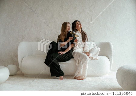 With drink, celebrating. Two happy young female best friends are indoors With drink, celebrating. Two happy young female best friends are indoors 131395045