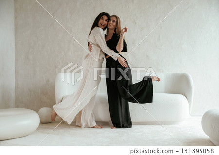 Standing and embracing each other. Two happy young female best friends are indoors Standing and embracing each other. Two happy young female best friends are indoors 131395058