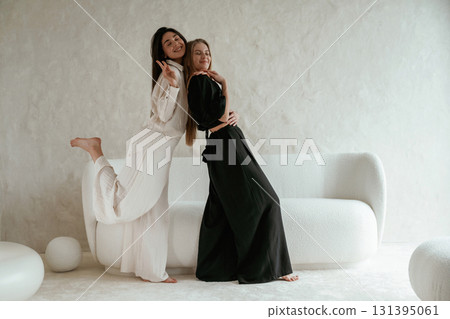 Standing and embracing each other. Two happy young female best friends are indoors 131395061