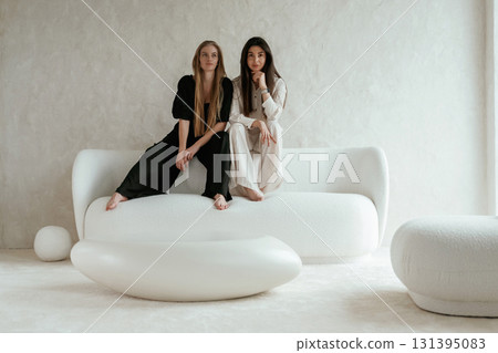 Resting, sitting together. Two happy young female best friends are indoors 131395083