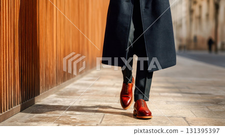 Stylish man walking on city sidewalk, wearing elegant coat and polished shoes, showcasing modern fashion and urban lifestyle 131395397