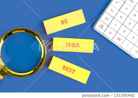 Copy space. Business concept. BE YOUR BEST made of wooden blocks on blue background next to calculator, top view Copy space. Business concept. BE YOUR BEST made of wooden blocks on blue background next to calculator, top view 131395492