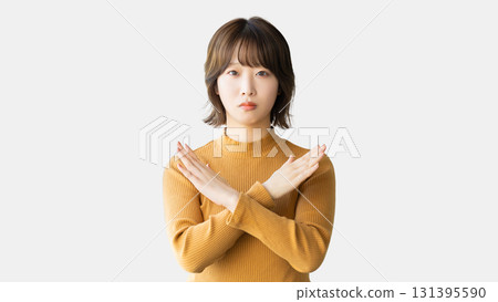 A woman with a troubled expression making a cross pose with her hands 131395590