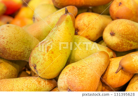 A pile of ripe juicy yellow pears displayed for sale on a supermarket vegetable counter. Demonstration of organic vegetarian and healthy food. Close-up A pile of ripe juicy yellow pears displayed for sale on a supermarket vegetable counter. Demonstration of organic vegetarian and healthy food. Close-up 131395628
