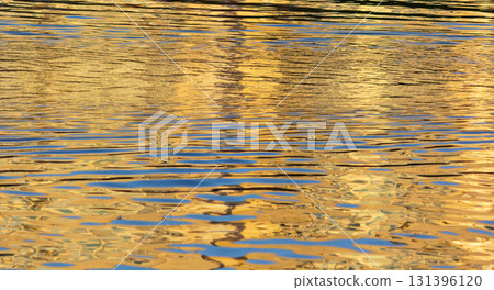 Reflection of a golden sunset and blue clouds in the water 131396120