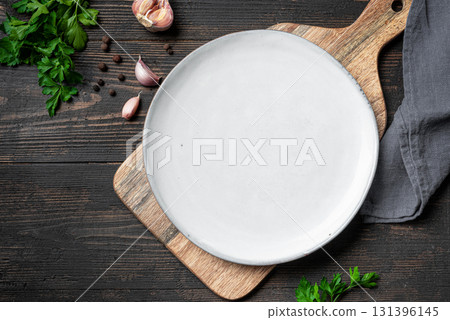 Empty white plate with herbs and garlic on wooden background 131396145