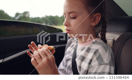little girl child eating burger in car, happy person, Happy childhood with burgers, Travel food essentials for families, Kid-friendly car meals, Snack time fun for young travelers, Nostalgic road trip 131396484