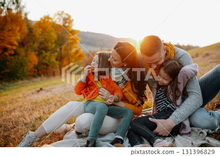 Parents with young children sitting outdoors in autumn light. 131396829