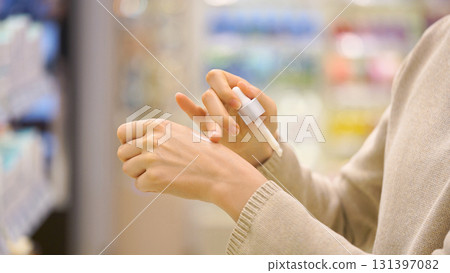 Female shopper checking ingredients while choosing cosmetic product in beauty store, testing facial serum with dropper on hand. Woman examining texture and quality. Concept of conscious choice 131397082