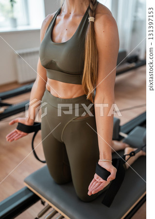 Woman doing pilates exercise on Pilates Reformer for the chest and back muscles, focusing on flexibility, strength, and control with determination Woman doing pilates exercise on Pilates Reformer for the chest and back muscles, focusing on flexibility, strength, and control with determination 131397153
