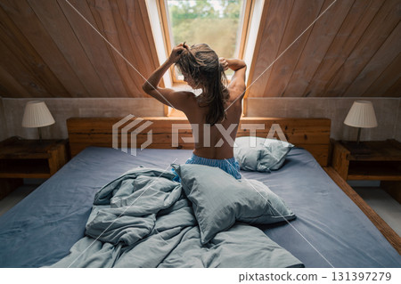 A tranquil morning scene showcasing a person gently awakening in a beautifully softly lit bedroom filled with comfort A tranquil morning scene showcasing a person gently awakening in a beautifully softly lit bedroom filled with comfort 131397279