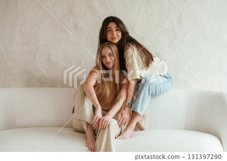 Front view, sitting. Two happy young female best friends are indoors Front view, sitting. Two happy young female best friends are indoors 131397290