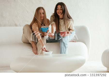 Tea and cookies. Two happy young female best friends are indoors 131397292